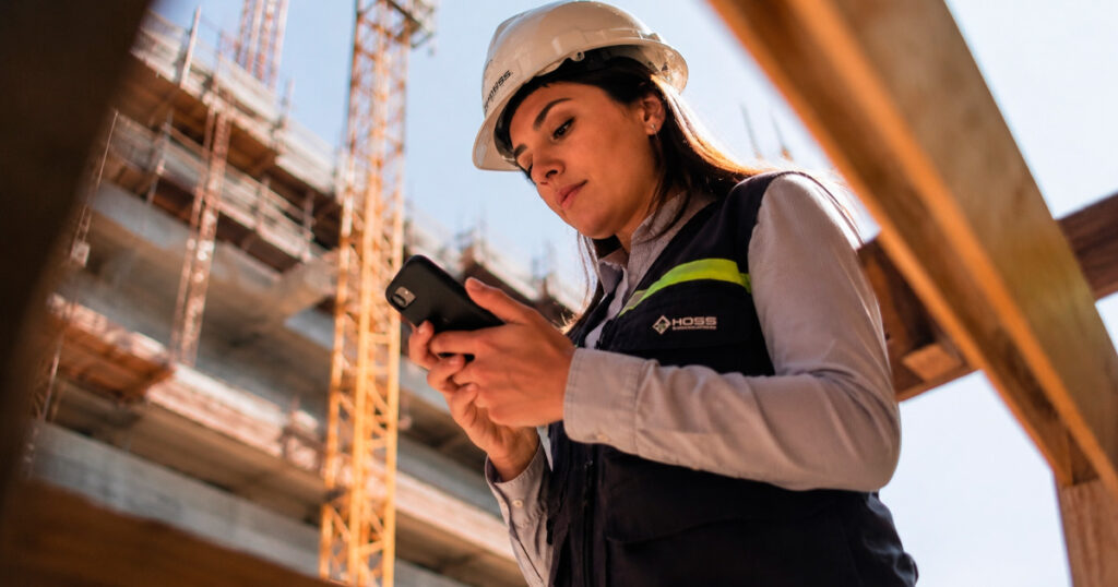 Engenheiro registrando o diário de obras digital pelo celular no canteiro de obras
